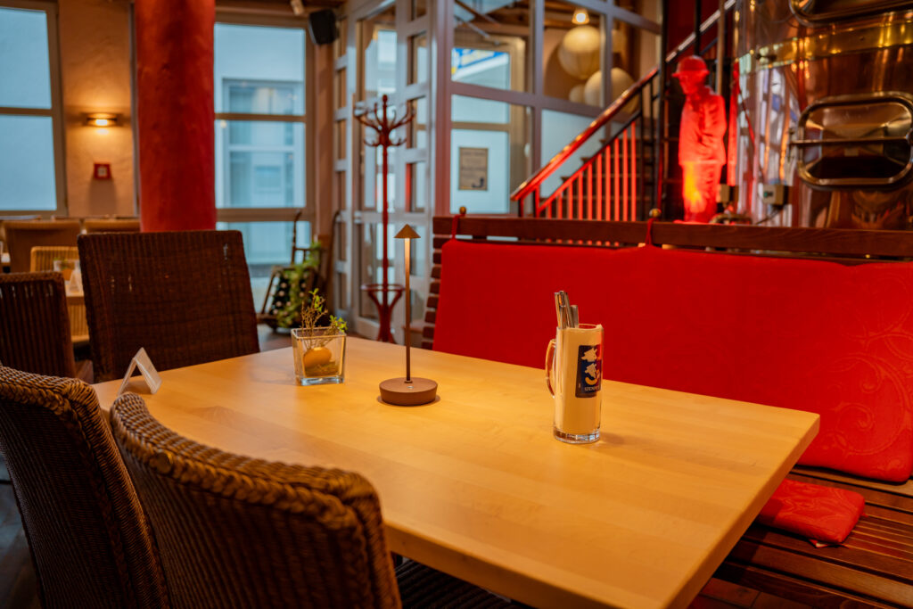 Gastraum im Stumm’s Brauhaus Neunkirchen mit Sudkessel und roter Sitzbank