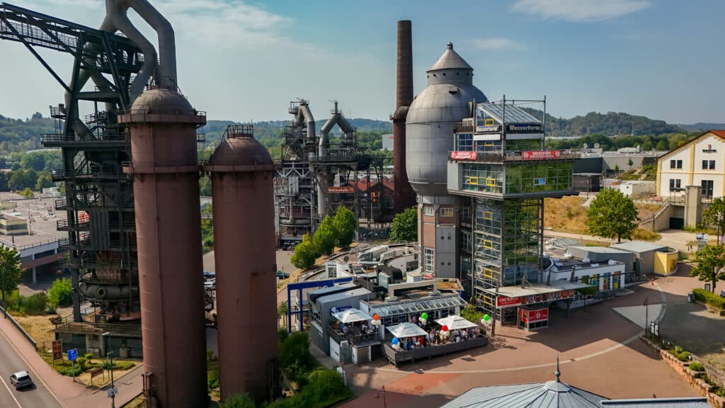 Drohnenaufnahme: Stumm’s Brauhaus mit Terrasse am Wasserturm in Neunkirchen, daneben die historischen Hochöfen